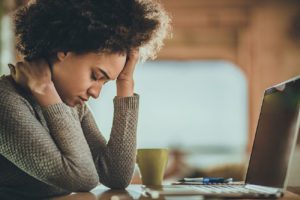 Woman holding her head in pain while working stress dentist in Virginia Beach Virginia 